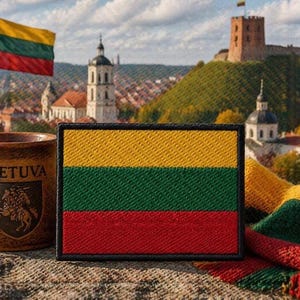 May include: A rectangular patch featuring the horizontal yellow, green, and red tricolor flag of Lithuania with a black border, positioned next to a brown ceramic mug with the text LIETUVA and a knight emblem, and a knitted tricolor scarf.