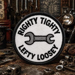 Puede incluir: Un parche bordado circular con fondo blanco y borde negro. El parche presenta un icono de llave inglesa gris en el centro, con el texto negro "RIGHTY TIGHTY" arqueado en la parte superior y "LEFTY LOOSEY" arqueado en la parte inferior.