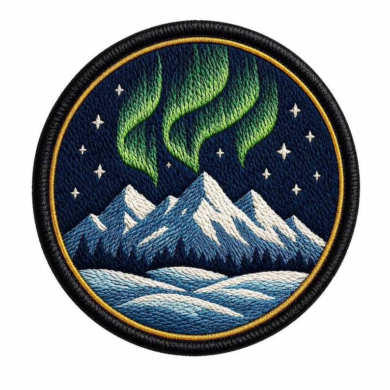 May include: A circular embroidered patch featuring a night sky with bright green aurora borealis and white stars above snow-capped blue mountains and a dark forest. The design is framed by a thin gold border and a thick black stitched edge.