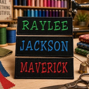 May include: Three rectangular black fabric patches with embroidered names. The top patch features the name RAYLEE in green, the middle patch features JACKSON in blue, and the bottom patch features MAVERICK in red, all in capital letters.