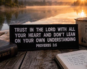 May include: A rectangular black patch with white embroidered text that reads: TRUST IN THE LORD WITH ALL YOUR HEART AND DON'T LEAN ON YOUR OWN UNDERSTANDING PROVERBS 3:5. The patch is positioned near a Holy Bible, a mug, and an open notebook.