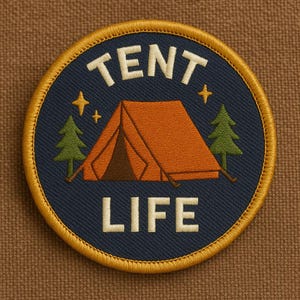 May include: Circular embroidered patch with a navy blue background and a gold border. The patch features an orange tent, two green trees, and the words "TENT LIFE" in white. Two gold stars are also included in the design.