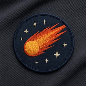 May include: Embroidered patch featuring a comet streaking across a navy blue background. The comet is depicted with a yellow sphere and orange and yellow flames. Gold stars are embroidered around the comet.