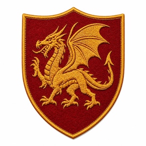 K&ouml;nnte beinhalten: Ein schildf&ouml;rmiger Stickaufn&auml;her mit einem goldenen Drachen auf einem dunkelroten Filzhintergrund. Der Drache ist im Profil mit ausgebreiteten Fl&uuml;geln, ausgestreckten Krallen und einem langen Schwanz dargestellt. Der Aufn&auml;her ist mit einem Goldfaden umrandet.