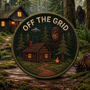 May include: A circular embroidered patch featuring a forest scene with a log cabin, a campfire, pine trees, a flying saucer, and a large creature. The text OFF THE GRID is stitched in light-coloured thread at the top of the dark green background.