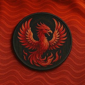 Può includere: Una toppa rotonda nera con un dettagliato disegno di fenice nei toni del rosso e dell'arancione. La fenice, con le ali spiegate e le fiamme, è ambientata su uno sfondo scuro. La toppa è su un tessuto rosso strutturato.