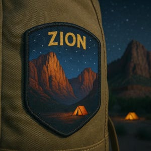 Puede incluir: Parche con la palabra "ZION" en letras doradas, que presenta una escena nocturna con montañas, un cielo estrellado y una tienda iluminada. El parche está cosido sobre una tela color caqui, sugiriendo un tema de camping o actividades al aire libre.