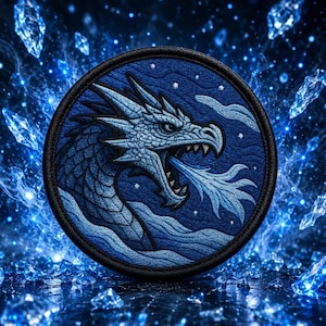 May include: A circular embroidered patch featuring a detailed blue dragon head in profile, exhaling a stream of light blue breath. The dragon is set against a dark blue background with small white stars and a black stitched border edge.