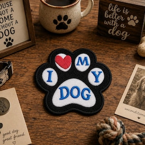 May include: A black paw-shaped patch with the words "I MY DOG" in blue and a red heart. The patch is surrounded by dog-themed items, including a framed sign, a mug, a wooden block, a dog tag, and a photo of a dog.