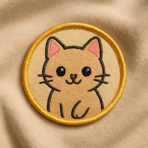 May include: Embroidered patch featuring a smiling cartoon cat with black whiskers, eyes, and outline. The cat has pink inner ears and is set against a tan background, framed by a gold border. The patch is circular.