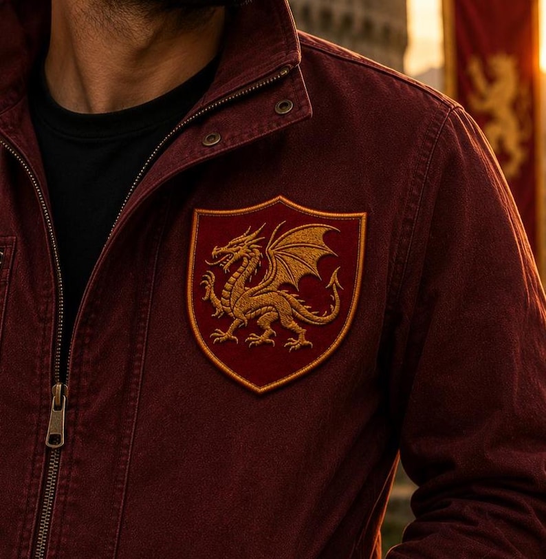K&ouml;nnte beinhalten: Eine dunkelrote Jacke mit Stehkragen, Metallrei&szlig;verschluss und einem auff&auml;lligen gestickten Aufn&auml;her auf der Brust. Der schildf&ouml;rmige Aufn&auml;her hat einen dunkelroten Hintergrund und zeigt einen detaillierten goldenen Drachen.