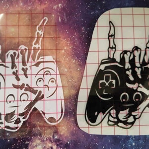 May include: Two black and white vinyl decals of a video game controller with a skeleton hand making the rock and roll hand gesture.