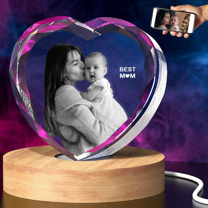 Puede incluir: Un cristal en forma de coraz&oacute;n con una foto de una madre y un ni&ntilde;o dentro. El cristal est&aacute; sobre una base de madera y tiene una luz en el interior. El texto "BEST MOM" est&aacute; grabado en el cristal.