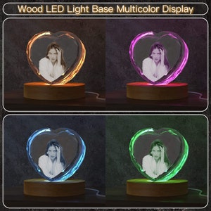 Puede incluir: Un cristal en forma de coraz&oacute;n con una foto en su interior se encuentra sobre una base de madera con una luz que cambia de color. La base de luz est&aacute; iluminada en amarillo, rosa, azul y verde.