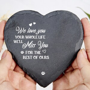 May include: A heart-shaped, dark grey slate memorial stone with white text that reads "We love you your whole life, we'll miss you for the rest of ours." Includes paw prints and hearts.