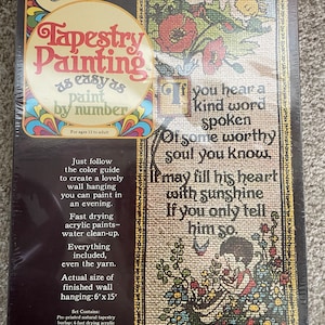 May include: Craft Master Tapestry Painting kit featuring a pre-printed natural tapestry burlap, 6 fast drying acrylic paints, an artist's brush, yarn, a numbered reference sheet, and complete instructions. The finished wall hanging measures 6 inches by 15 inches. The image shows a colorful tapestry with a quote: "If you hear a kind word spoken of some worthy soul you know, it may fill his heart with sunshine if you only tell him so."