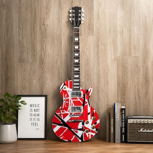May include: An electric guitar featuring a vibrant red, white, and black striped pattern across its body. The instrument has a dark fretboard with white rectangular inlays, chrome hardware, two humbucker pickups, and four circular control knobs.