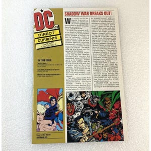 May include: A DC Comics comic book cover with the title "Direct Currents" and the date "January Cover Date." The cover features Superman and other characters, with text detailing the "Shadow War" storyline.