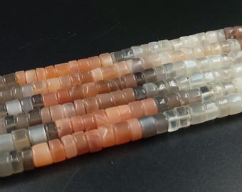 Può includere: Una collana di perle di pietra di luna di colore pesca chiaro, grigio e bianco. Le perle sono sfaccettate e hanno una forma quadrata.