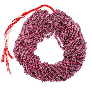 Puede incluir: Una hebra de cuentas de rubí rosa en forma de chip, de aproximadamente 38 cm de largo, con un cordón rojo atado.