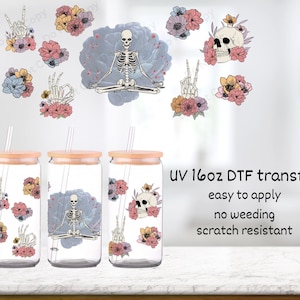 May include: Three 16oz clear glass tumblers with bamboo lids and straws, featuring a floral and skeleton design. The tumblers are on a light brown surface. UV 16oz DTF transfer, easy to apply, no weeding, scratch resistant.