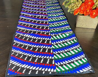 Peut inclure: Un chemin de table noir et blanc avec un motif géométrique de triangles bleus, rouges, verts et blancs. Le chemin de table est en tissu et a une bordure noire.