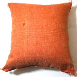 Op de afbeelding: Een effen oranje kussen met een licht getextureerd oppervlak. Het kussen is gemaakt van geweven stof en heeft een eenvoudig, ingetogen ontwerp.