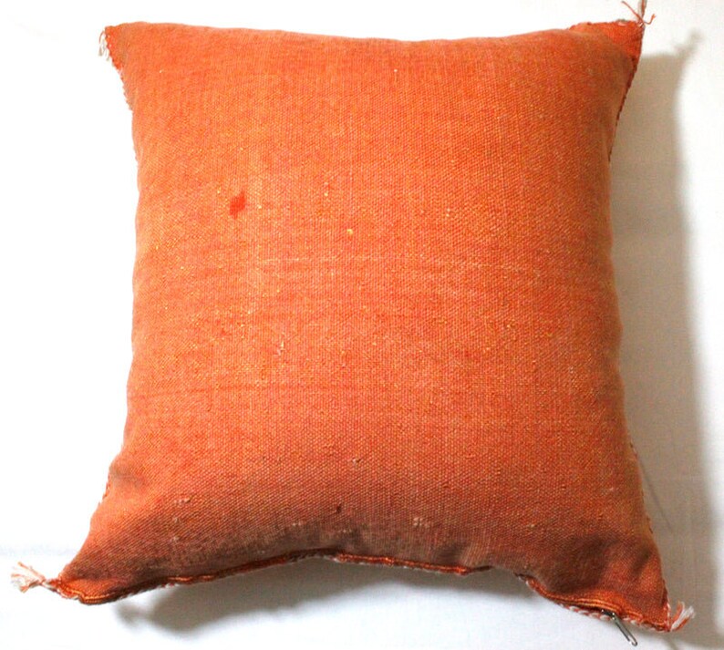 Op de afbeelding: Een effen oranje kussen met een licht getextureerd oppervlak. Het kussen is gemaakt van geweven stof en heeft een eenvoudig, ingetogen ontwerp.
