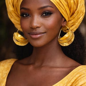 May include: A woman wearing a yellow turban and matching top. She is wearing large, gold hoop earrings. The woman has dark skin and is smiling. The background is blurred.