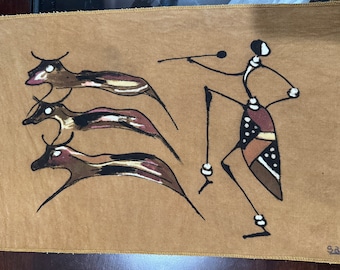 Peut inclure: Une tapisserie murale en tissu brun avec une illustration stylisée en noir et blanc d'une personne dansant avec trois animaux. La personne porte une jupe à motifs et un collier. Les animaux sont stylisés et ont de longs cous et des queues.