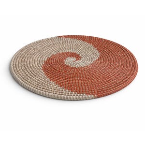 Könnte beinhalten: Ein runder, gewebter Platzdeckchen mit einem Spiralmuster. Der Platzdeckchen ist in zwei Bereiche unterteilt: einen in Naturbeige und einen in einem rot-orangen Farbton. Das Spiralmuster erzeugt einen optisch ansprechenden Kontrast. Ca. 30 cm Durchmesser.