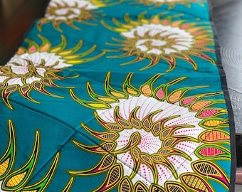 Peut inclure: Un chemin de table turquoise avec un motif répétitif de fleurs stylisées blanches, jaunes, orange, roses et brunes. Les fleurs ont un design en spirale et sont soulignées de noir.