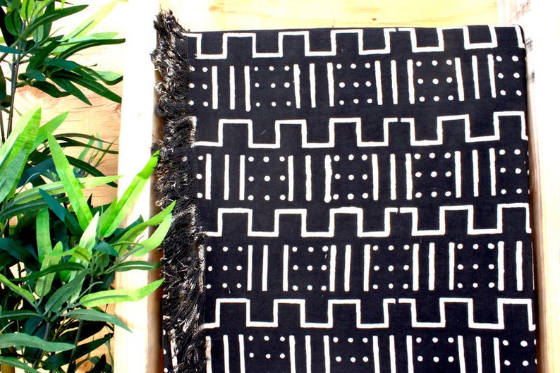 K&ouml;nnte beinhalten: Schwarz-wei&szlig;e Tagesdecke mit geometrischem Muster. Die Decke hat einen Fransenrand.