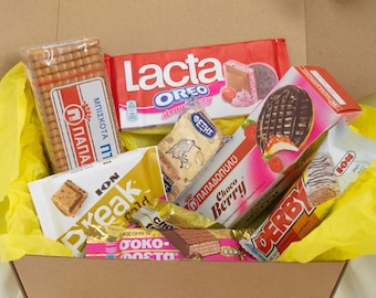 Può includere: Una scatola regalo gialla piena di diverse barrette di cioccolato e biscotti. La scatola contiene marchi come Lacta, Oreo, Papa, Choco Berry, Derby e Toko-Festa.