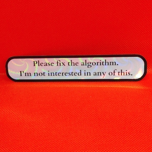 May include: A rectangular sticker with rounded corners, featuring the text "Please fix the algorithm. I'm not interested in any of this." The sticker has a holographic, iridescent background and a black border. The background is a bright orange.