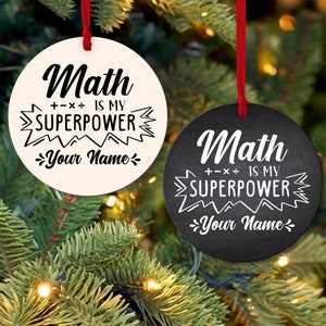 May include: Two round Christmas ornaments with a white background and a black background. Both ornaments have the text "Math is my superpower" with a stylized graphic of lightning bolts. The text "Your Name" is at the bottom of each ornament.