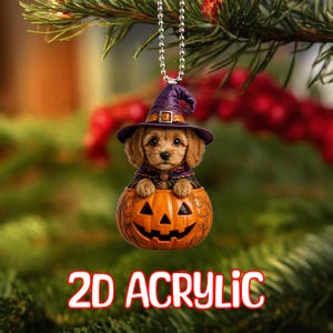 May include: A 2D acrylic hanging ornament featuring a brown puppy wearing a purple witch hat and cape, sitting inside an orange jack-o'-lantern pumpkin. The ornament is suspended by a silver ball chain and displays the text 2D ACRYLIC at the bottom.