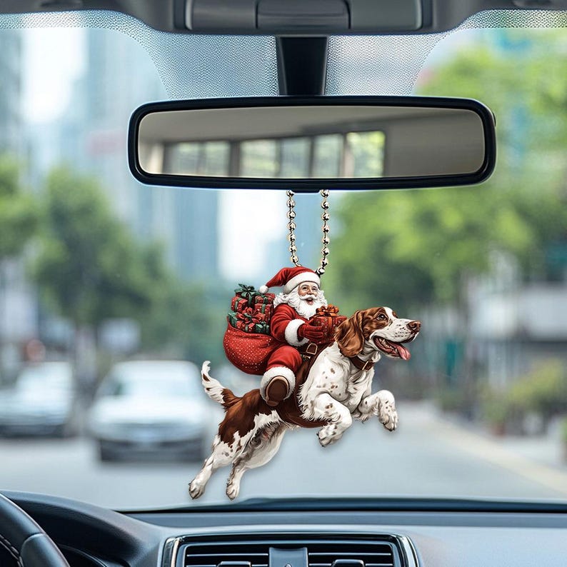 May include: A red and white Christmas car ornament featuring Santa Claus riding a brown and white dog. Santa is holding a bag of presents and a gift.
