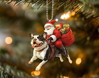 Könnte beinhalten: Ein Weihnachtsbaumschmuck mit einem Weihnachtsmann, der auf einem schwarz-weißen französischen Bulldoggen reitet. Der Weihnachtsmann trägt einen roten Anzug mit weißen Verzierungen und einen weißen Bart. Er hält einen Sack mit Geschenken und lächelt. Der Schmuck ist aus Keramik und etwa 7,5 cm hoch.