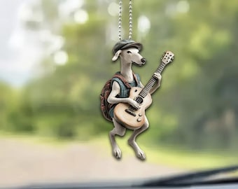 May include: A white dog figurine wearing a blue shirt and a brown backpack plays a brown acoustic guitar. The figurine is hanging from a silver chain.