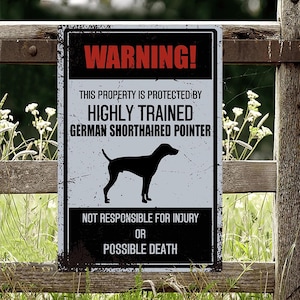 May include: A warning sign with black text on a white background. The sign reads "WARNING! This property is protected by highly trained German Shorthaired Pointer. Not responsible for injury or possible death."