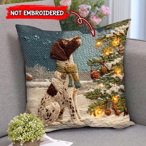 Könnte beinhalten: Dekoratives quadratisches Kissen mit einem Hund mit braunen und weißen Flecken, der einen Schal trägt und einen Weihnachtsbaum betrachtet. Die Winterlandschaft zeigt Schnee und einen blauen Himmel. Der Text "NOT EMBROIDERED" ist sichtbar.