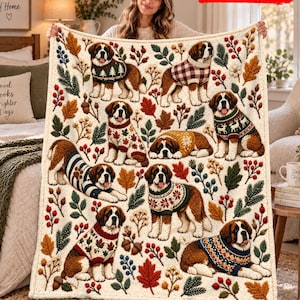 Peut inclure: Un plaid couleur crème orné d'un motif répétitif de chiens Saint-Bernard portant divers pulls à motifs, entremêlés de feuilles d'automne, de branches de pin et de baies rouges. Le texte 2D FLAT PRINTED est visible.