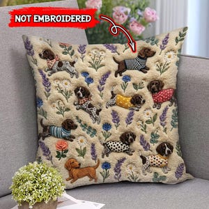 May include: A decorative beige throw pillow featuring a repeating pattern of dachshunds and other dogs wearing sweaters and bandanas, surrounded by floral elements like lavender and daisies. The text "NOT EMBROIDERED" is visible.