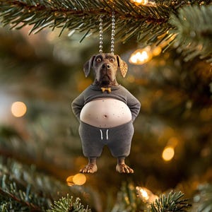 May include: A brown and white dog wearing a gray outfit with a bow tie, hanging from a silver chain on a Christmas tree.