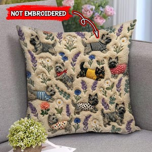 Puede incluir: Un cojín decorativo con un patrón repetido de perros terrier con varios atuendos, intercalados con elementos florales como lavanda y margaritas. El cojín tiene un fondo texturizado blanquecino.