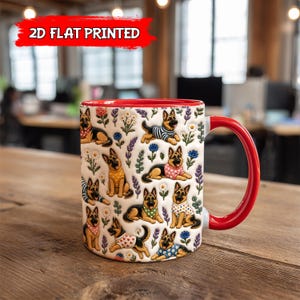 May include: A white ceramic mug with a red interior and handle, featuring a repeating pattern of German Shepherd dogs wearing various patterned shirts and bandanas, interspersed with colorful floral illustrations and the text 2D FLAT PRINTED.