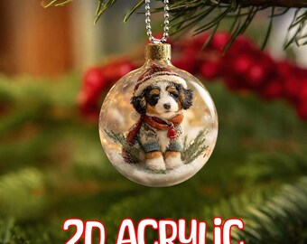 Può includere: Una decorazione natalizia in acrilico trasparente con un cucciolo che indossa un cappello, una sciarpa e un maglione all'interno di una palla di neve. L'ornamento è appeso a una catena d'argento. Il testo "2D ACRYLIC" è visualizzato in rosso e bianco.
