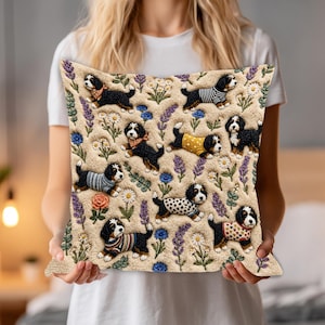 Op de afbeelding: Rechthoekig sierkussen met een herhalend patroon van Berner Sennenhond puppy's in verschillende outfits, tegen een beige achtergrond met bloemen- en lavendelaccenten. Het kussen is gemaakt van een textuurstof.