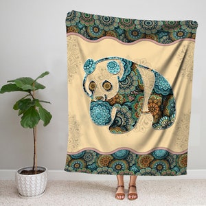May include: A cream-colored throw blanket with a blue and green mandala pattern featuring a panda bear silhouette. The panda is also decorated with a mandala pattern.